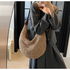 Detail of hand-woven straw hobo bag with adjustable brown leather shoulder strap