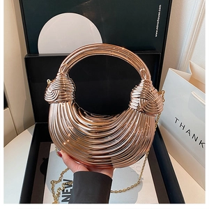 Detailed view of rose gold crescent metal handbag with radial texture and knot handle