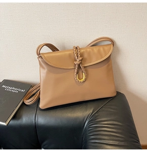 Detail of camel faux leather bag showing woven rope knot and golden U-shaped buckle