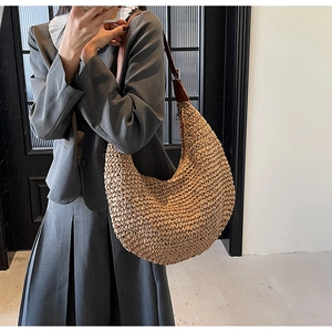 Detail of hobo straw bag showing textured weave pattern and brown leather strap