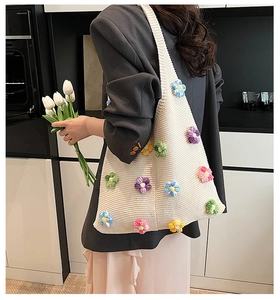 Détail d'un sac cabas en tricot avec des fleurs crochetées 3D et texture douce