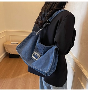Close-up of the silver buckle and metal chain strap on this dark blue denim tote bag