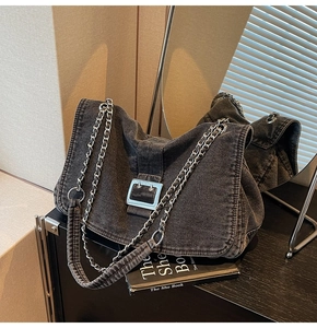Close-up of charcoal denim flap bag with metal chain strap and large silver buckle