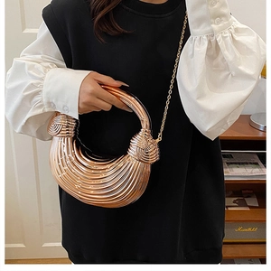 Detailed view of rose gold metallic wavy texture and knot handle on acrylic evening bag