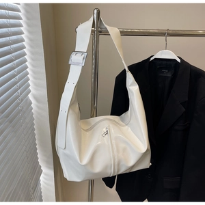 Détail d'un cabas en cuir verni blanc montrant la bandoulière large et la boucle argentée