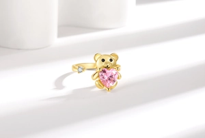 Vue détaillée d'une bague ours dorée avec pierre rose en cœur et détails en zircon blanc