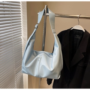 Détail de la large bandoulière réglable et de la boucle en métal argenté sur le sac bleu
