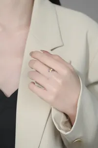 Vue détaillée d'une bague patte de chat avec cœur jaune portée sur un blazer beige