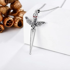 Gothic dagger pendant necklace with skull wings and red stone on white pedestal