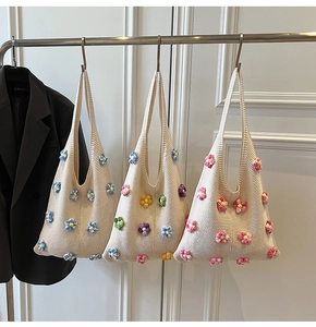 Détail de trois sacs cabas faits main au crochet avec motifs floraux sur un support