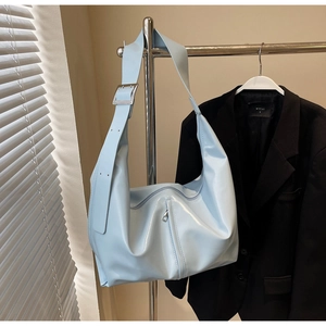 Détail du sac hobo en cuir verni bleu clair avec boucle argentée et texture brillante