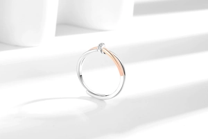 Dettaglio anello a nodo con finiture in oro rosa e pavé su gradini geometrici bianchi