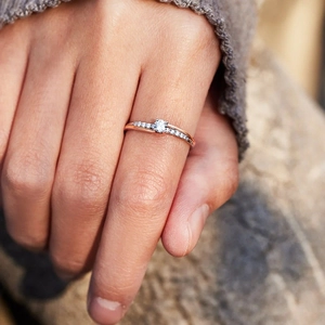 Close-up of rose gold crossover ring with micro-pave zircons on a model's finger