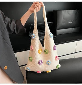 Détail d'un sac à bandoulière en tricot crème avec des décorations florales 3D colorées
