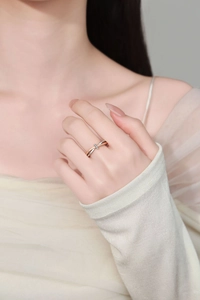 Primo piano dell'anello a nodo bicolore in argento e oro rosa con tre piccoli zirconi