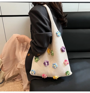 Détail d'un sac fourre-tout en tricot crème avec des fleurs colorées en crochet 3D et sangle