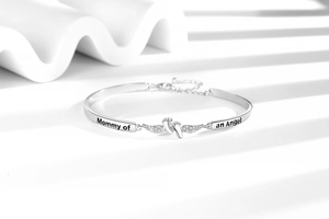 Detailansicht des Mommy of an Angel Armbands mit Engelsflügeln auf modernem weißem Grund