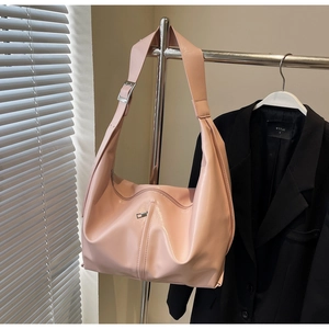 Détail d'un sac à bandoulière en similicuir rose avec large sangle et boucle argentée