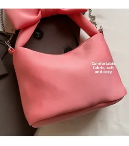 Close-up of pink silk shoulder bag with large bow decoration and silver metal chain
