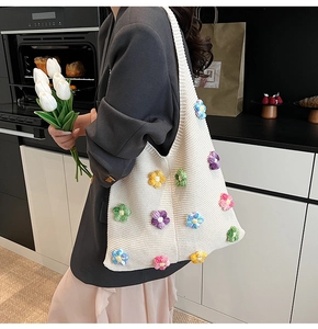 Détail d'un sac fourre-tout beige tricoté avec des fleurs au crochet colorées et bandoulière
