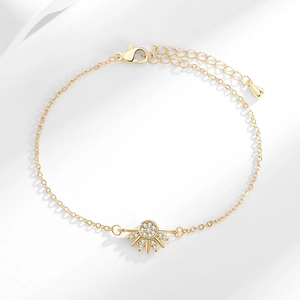 Golden sun charm bracelet with white zircon stones on a minimalist white background