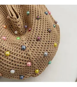 Detailed close-up of khaki woven tote bag featuring iridescent pearl beads and knit texture