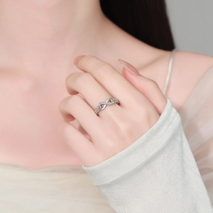 Elegant infinity-shaped silver ring with sparkling cubic zirconia on female finger