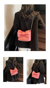 Detailed view of pink bow-shaped crossbody bag with slim silver chain strap