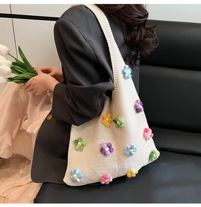 Détail d'un sac cabas en crochet crème avec fleurs tricotées colorées en 3D