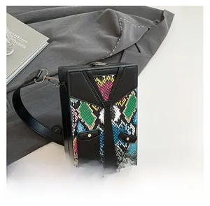 Detail view of box-shaped shoulder bag featuring tie design and colorful snake pattern