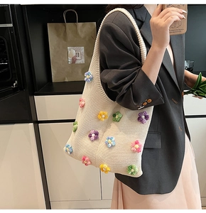 Gros plan du sac cabas en tricot beige avec des décorations de fleurs colorées en 3D