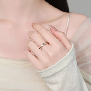 Elegante anello a nodo bicolore con piccoli diamanti mostrato sul dito in stile sobrio