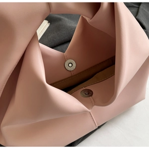 Close-up of pink PU handbag showing magnetic closure, stitching and knotted handle