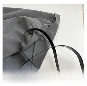 Detail of grey twill texture fabric with white topstitching and thin black leather strap