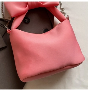 Close-up of pink bow handbag with premium silk texture and silver chain strap details