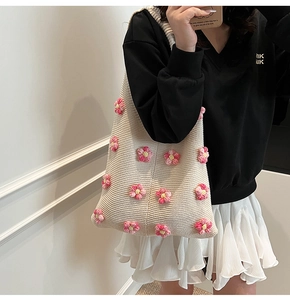 Détail du sac cabas en tricot crème avec fleurs 3D roses sur l'épaule du modèle
