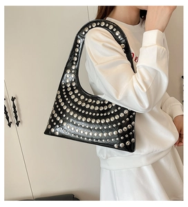 Close-up of black punk style crescent shoulder bag with silver metal rivet studs