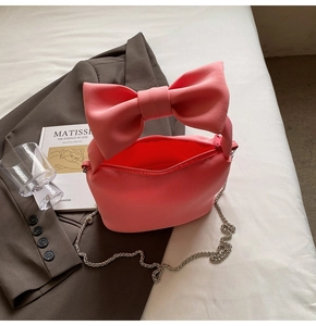 Close-up of pink bow handbag with silver chain strap and soft cloud-like texture