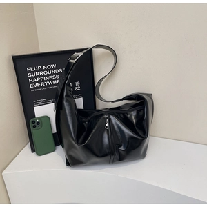 Détail du sac à bandoulière noir brillant en forme de croissant avec fermeture éclair frontale