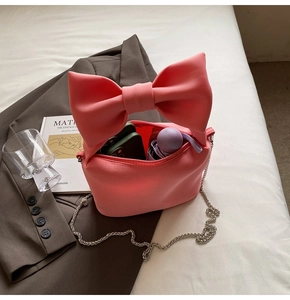 Detailed view of pink bow handbag with silver chain strap and interior storage capacity