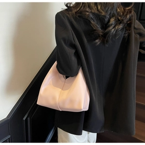Pink minimalist handbag with central stitching detail held by model in black blazer