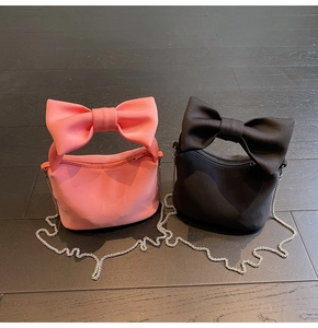 Detail showing soft nylon fabric with large bow handle and silver chain on small crossbody bags