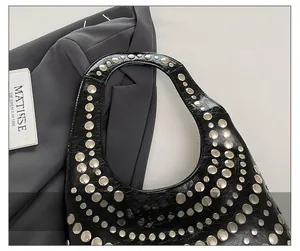 Detail view of the soft studded handle on black lychee grain leather punk shoulder bag