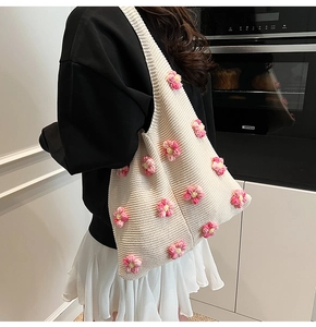 Gros plan d'un sac à bandoulière en maille crème avec fleurs 3D et texture douce
