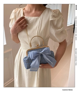 Close-up of blue tweed handbag featuring a gold metal chain and a large chiffon bow