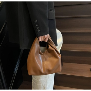 Detail of minimalist dark brown leather handbag with soft pleated design and sewing crafts