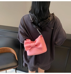 Detailed view of pink bow chain bag with soft suede texture and silver metal hardware