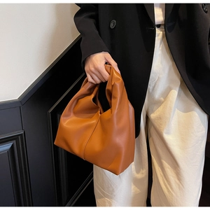 Close-up of a brown croissant handbag held by a model for a modern commute style