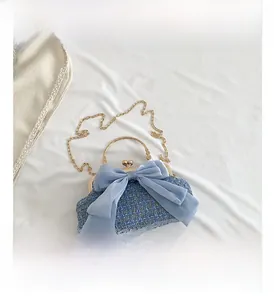 Detail view of blue tweed evening bag featuring a chiffon bow and gold metal handle