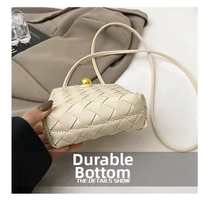 Detail shot of the reinforced wear-resistant base on a beige woven leather shoulder bag